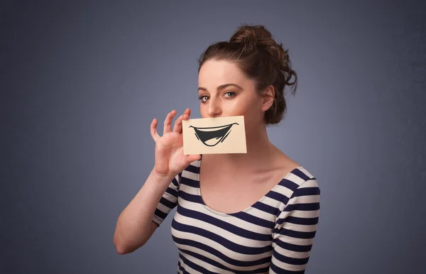 Happy cute girl holding paper with funny smiley drawing — Stock Photo, Image