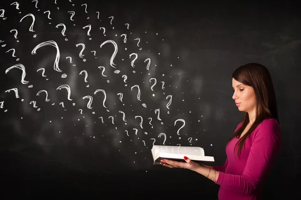 Pretty woman reading a book with question marks coming out from — Stock Photo, Image