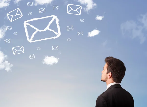 Empresário olhando para o símbolo de correio nuvens no céu azul — Fotografia de Stock