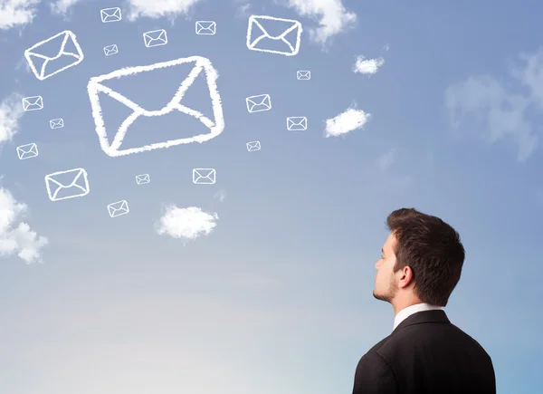 Hombre de negocios mirando el símbolo de correo nubes en el cielo azul —  Fotos de Stock