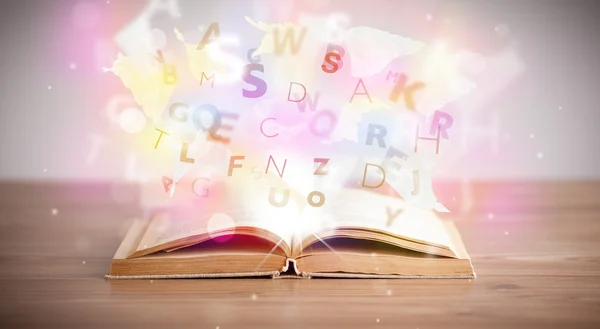 Aufgeschlagenes Buch mit leuchtenden Buchstaben auf Betongrund — Stockfoto