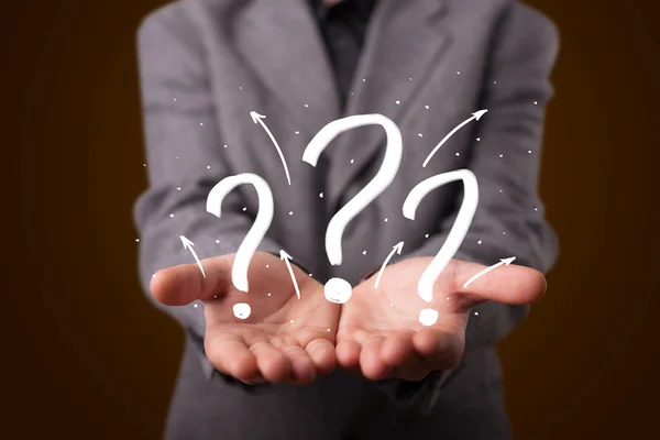 Young businessman presenting hand drawn question marks — Stock Photo, Image