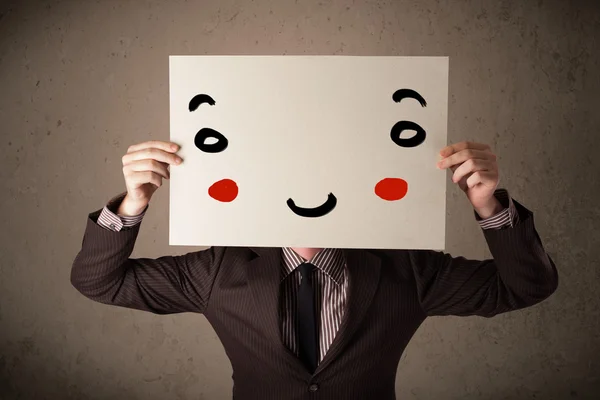 Empresário segurando um papelão com uma cara sorridente — Fotografia de Stock