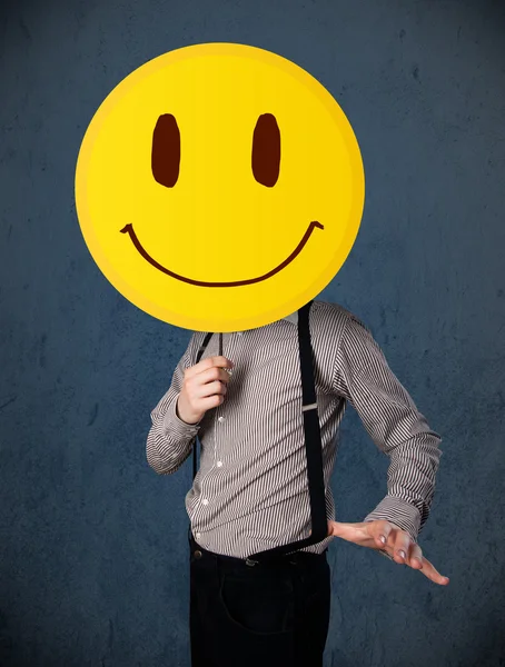 Uomo d'affari che tiene un faccina faccina sorridente — Foto Stock