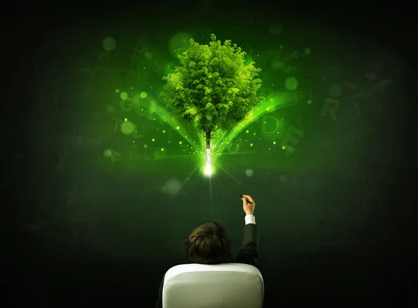 Businessman in chair sitting in front of a glowing tree — Stock Photo, Image
