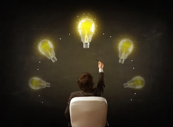 Businessman sitting with lightbulbs over his head — Stock Photo, Image