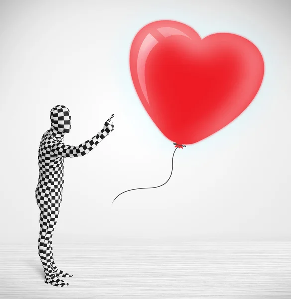 Cute guy in morpsuit body suit looking at a balloon shaped heart — Stock Photo, Image