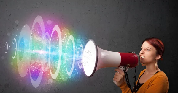 Ung flicka skriker i en högtalare och färgglada energi strålar com — Stockfoto