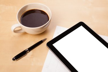 Boş alanı olan bir tablet bilgisayar ve masada bir fincan kahve.