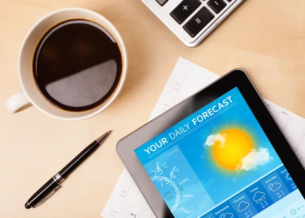 Tablet pc showing weather forecast on screen with a cup of coffe — Stock Photo, Image