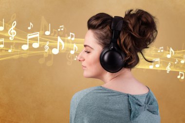 Kulaklıklı genç bir kadın müzik dinliyor.