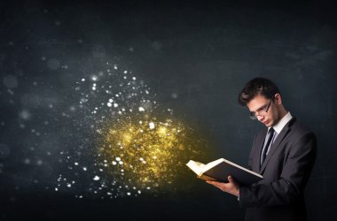 Genç adam sihirli bir kitap okuyor.