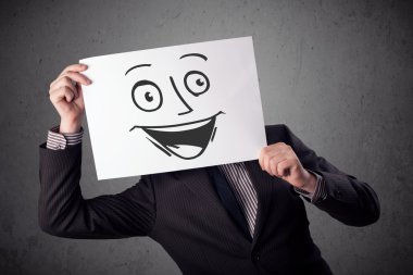 empresario sosteniendo una cartulina con cara sonriente en él en frente