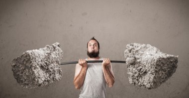 Sıska adam büyük taş ağırlıkları kaldırıyor.