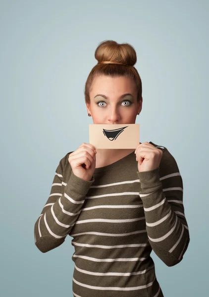 Happy cute girl holding paper with funny smiley drawing — Stock Photo, Image