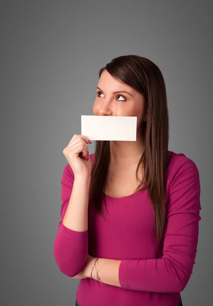 Симпатичная девушка держит белую карточку перед губами с копировальным аппаратом. — стоковое фото
