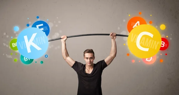 Muscular man lifting colorful vitamin weights — Stock Photo, Image