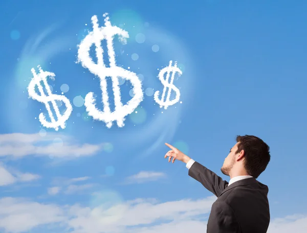 Empresario apuntando a nubes de signo de dólar en el cielo azul —  Fotos de Stock