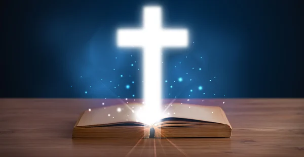 Open holy bible with glowing cross in the middle — Stock Photo, Image