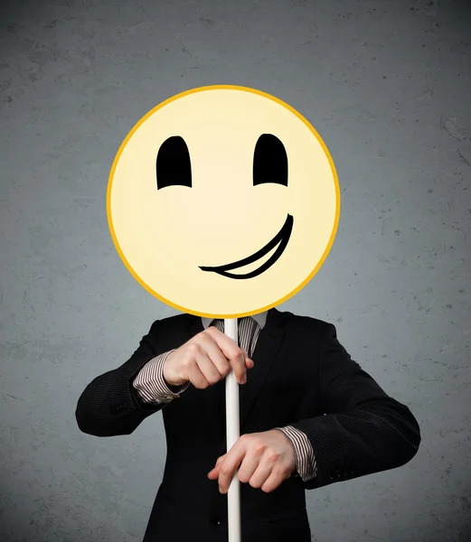 Empresario sosteniendo un emoticono sonriente — Foto de Stock