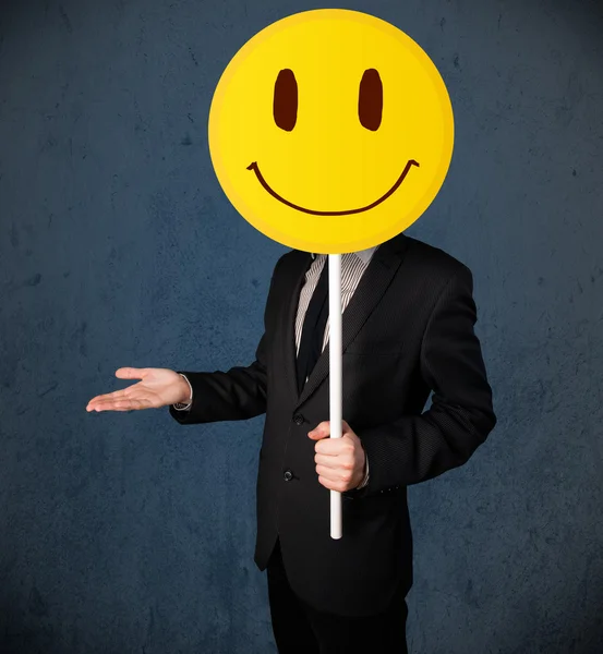 Businessman holding a smiley face emoticon — Stock Photo, Image