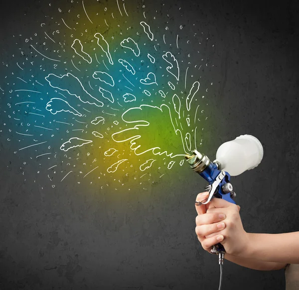 Worker with airbrush gun paints colorful lines and splashes — Stock Photo, Image