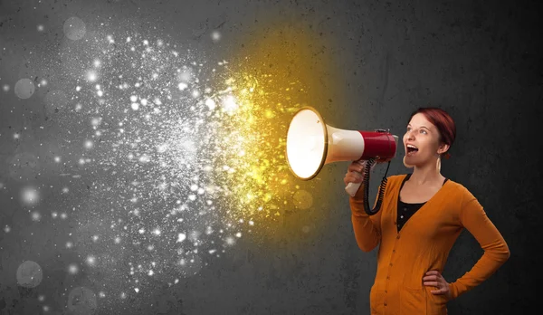 Woman shouting into megaphone and glowing energy particles explo — Stock Photo, Image