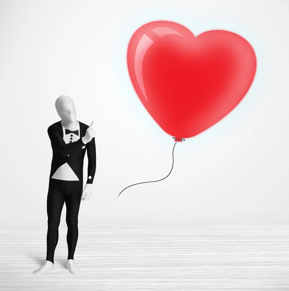 Bonito cara em terno morpsuit corpo olhando para um coração em forma de balão — Fotografia de Stock