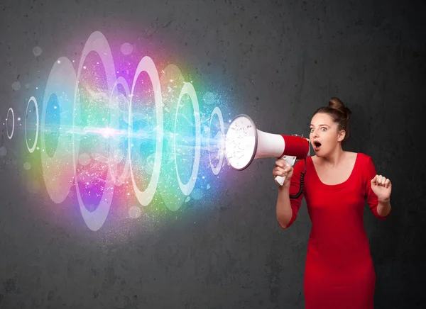 Young girl yells into a loudspeaker and colorful energy beam com — Stock Photo, Image