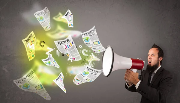 Guy yelling into loudspeaker and newspapers fly out — Stock Photo, Image