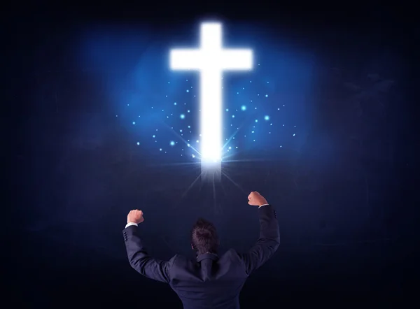 Businessman in front of a glowing cross — Stock Photo, Image