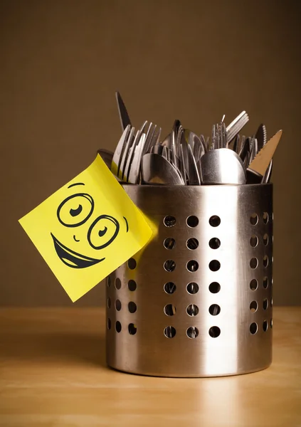 Post-it notera med smiley ansikte klistras på bestick fall — Stockfoto