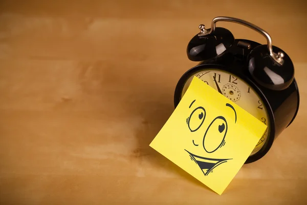 Post-it con faccina sorridente incollata su un orologio — Foto Stock