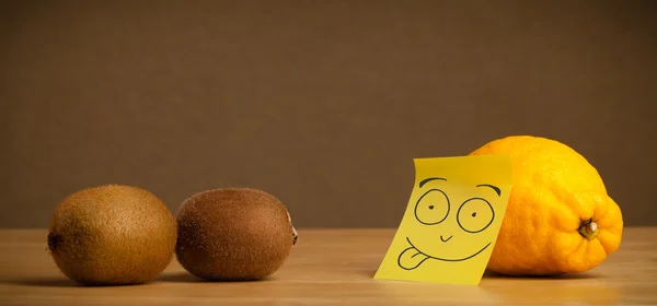 Lemon with post-it note sticking out tongue to kiwis — Stock Photo, Image