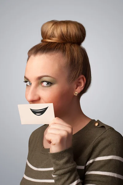 Happy pretty woman holding card with funny smiley — Stock Photo, Image