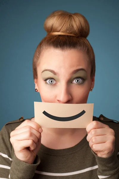 Happy pretty woman holding card with funny smiley — Stock Photo, Image