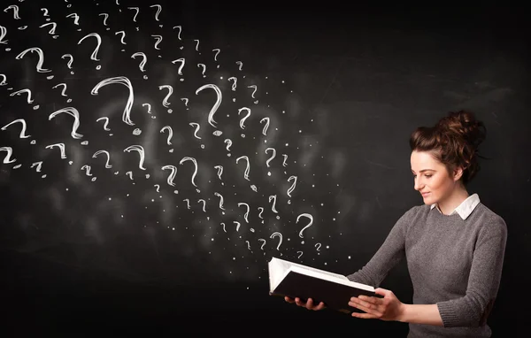 Pretty woman reading a book with question marks coming out from — Stock Photo, Image