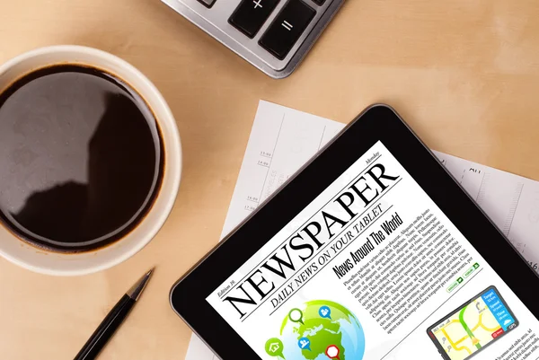 Tablet pc toont nieuws op het scherm met een kopje koffie op een bureau — Stockfoto