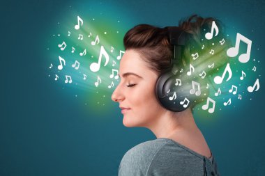 Kulaklıklı genç bir kadın müzik dinliyor.