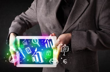 Tableti grafik ve grafik sembolleriyle tutan genç kişi