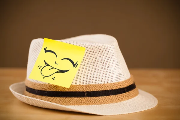 Nota post-it con la cara sonriente pegada en un sombrero —  Fotos de Stock