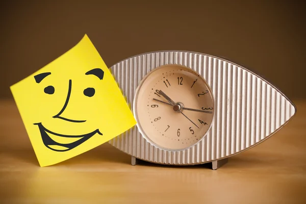 Nota post-it con la cara sonriente pegada en un reloj — Foto de Stock