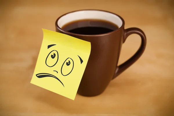 Post-it notera med smiley ansikte klistras på cup — Stockfoto