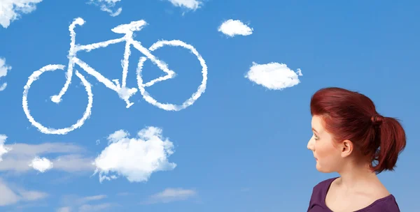 年轻的女孩低头看自行车在蓝蓝的天空上的云 — 图库照片