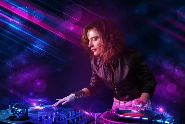 Young DJ playing on turntables with color light effects — Stock Photo, Image