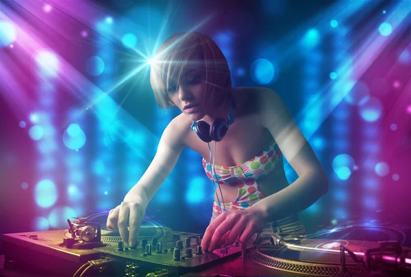 Dziewczyna DJ miksowania muzyki w klubie z niebieski i fioletowy światła — Zdjęcie stockowe