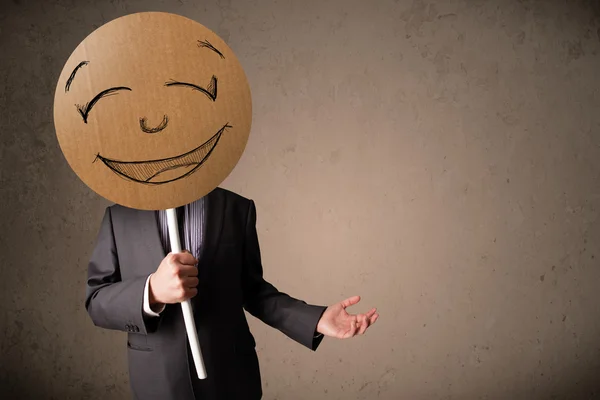 Affärsman som innehar en smiley face styrelse — Stockfoto