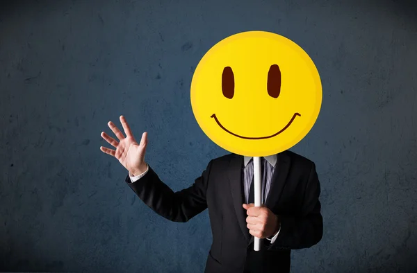 Επιχειρηματίας κρατώντας ένα χαμογελαστό φατσούλα emoticon — Φωτογραφία Αρχείου
