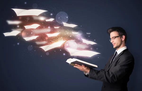 Joven leyendo un libro con sábanas voladoras saliendo del bo — Foto de Stock