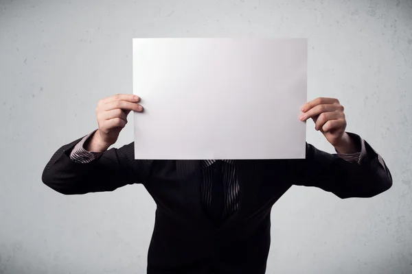 Businessman holding in front of his head a paper with copy space — Stock Photo, Image